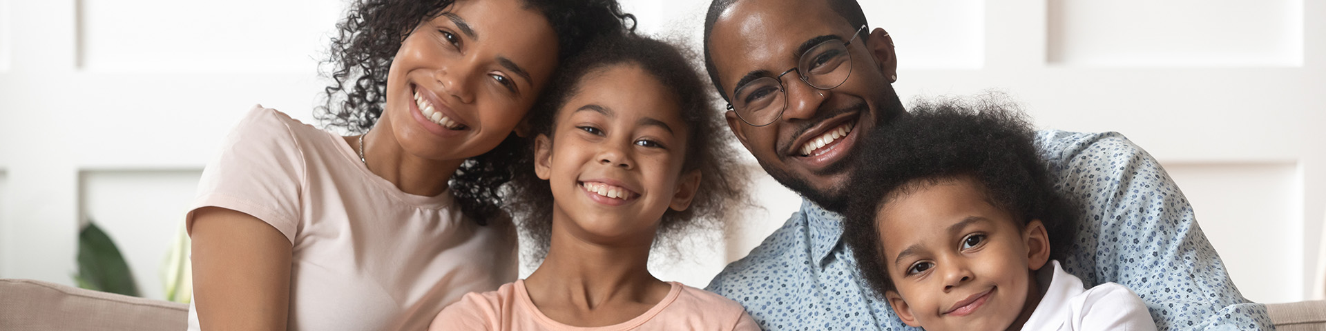 black family with two parents and two children sitting together and smiling 