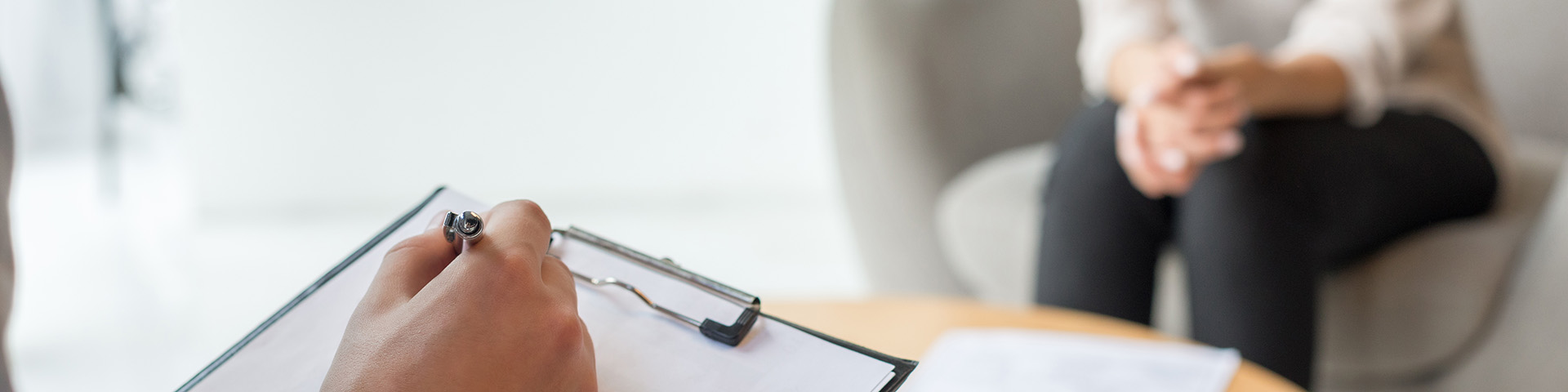 psychologist writing on clipboard across from patient